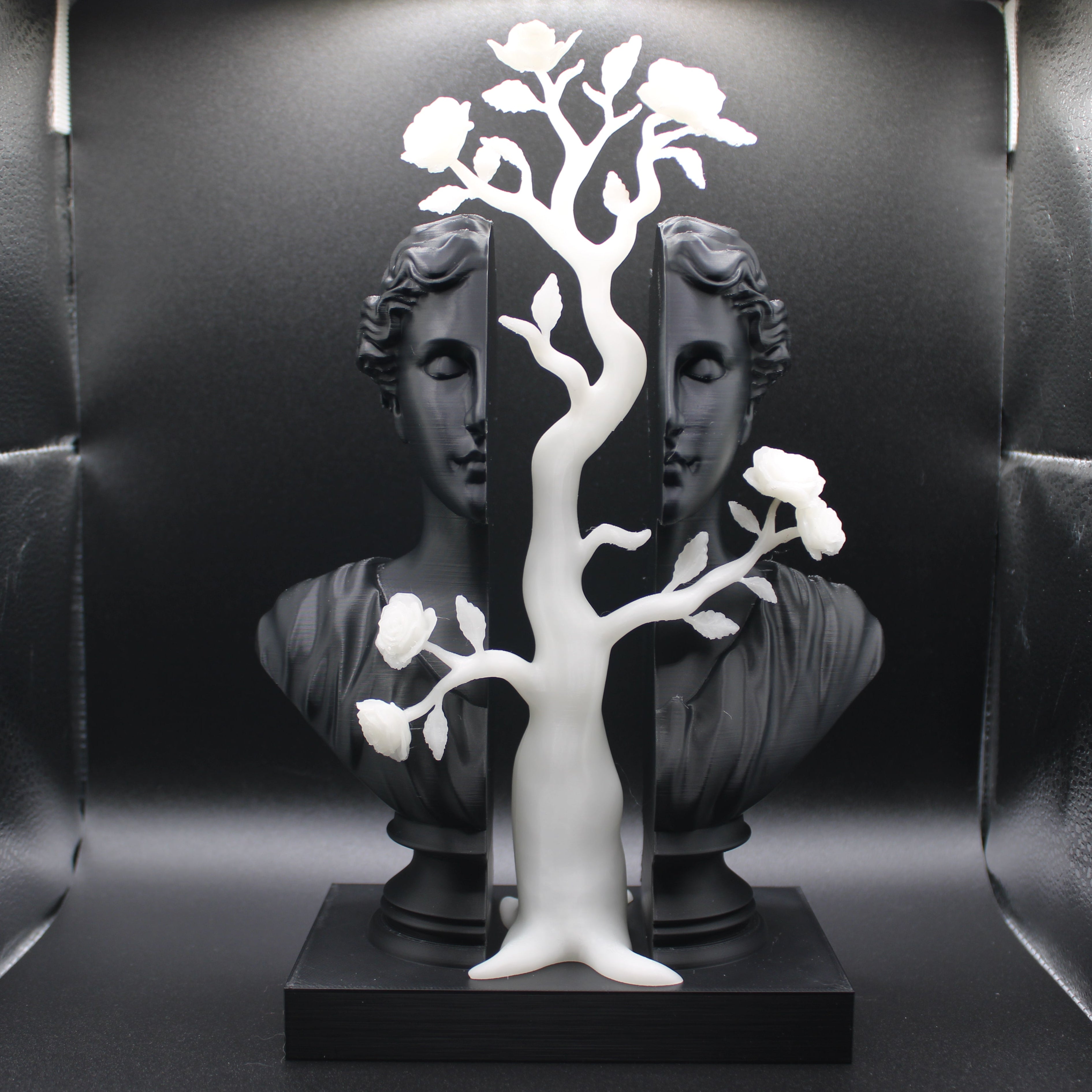 Decorative sculpture with white tree-like structure on a black base against a reflective black background