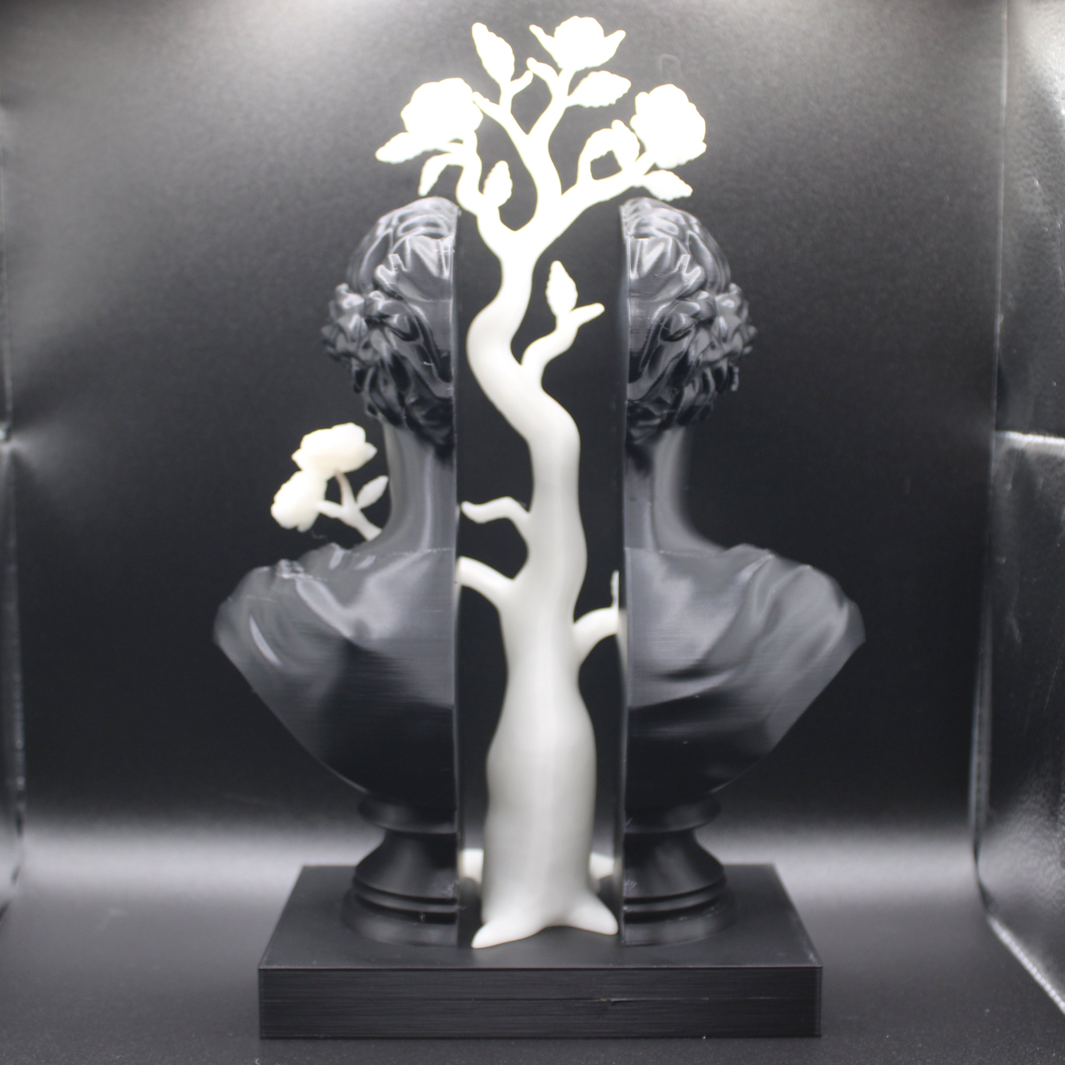 Decorative metal tree sculpture with flowers on a black background