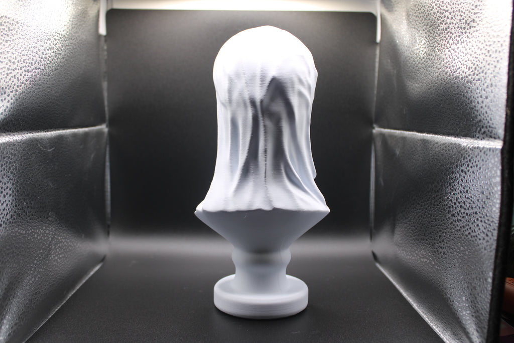 White sculpture of a head with a veil on a black background
